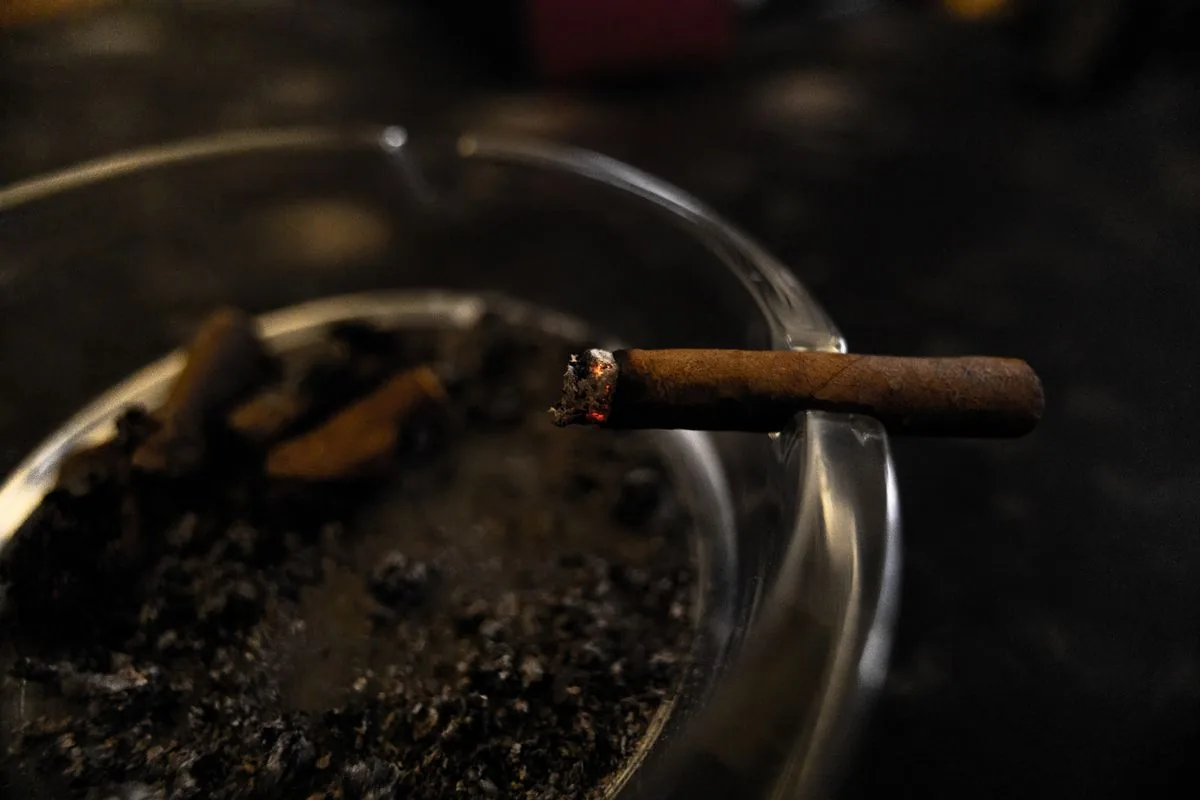 Cigarette burning in an ashtray, a habit that stains teeth and raises the risk of gum disease