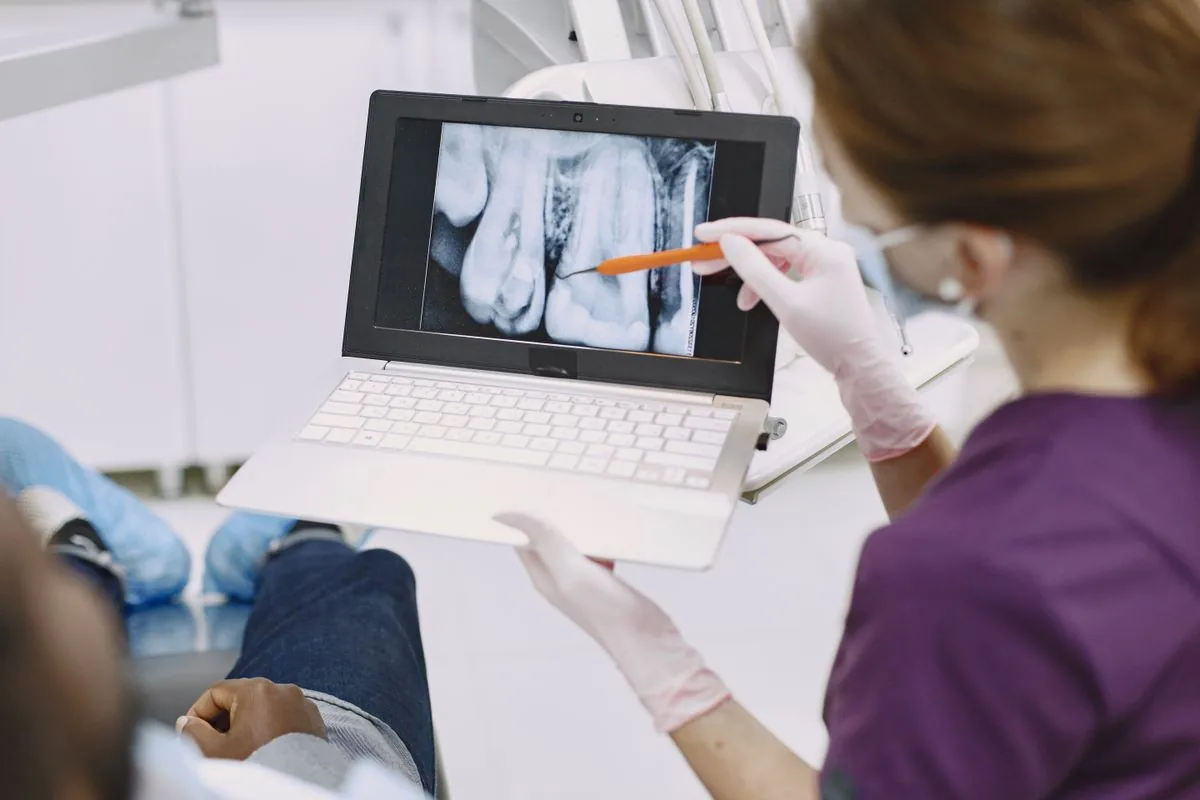 Dentist explaining a dental x-ray to show why a tooth may need extraction
