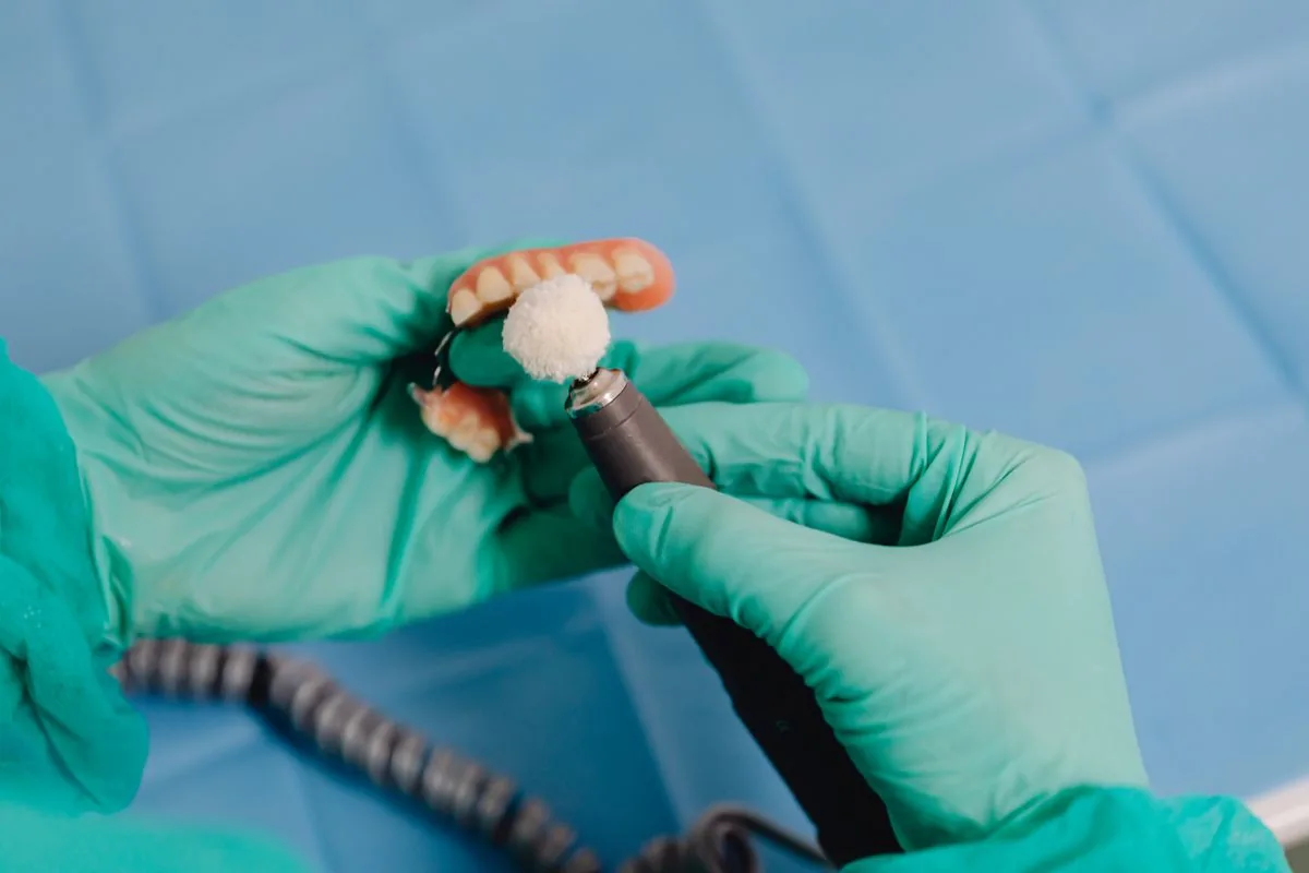 Gloved hands polishing a custom denture, the kind of detail that goes into full and partial dentures