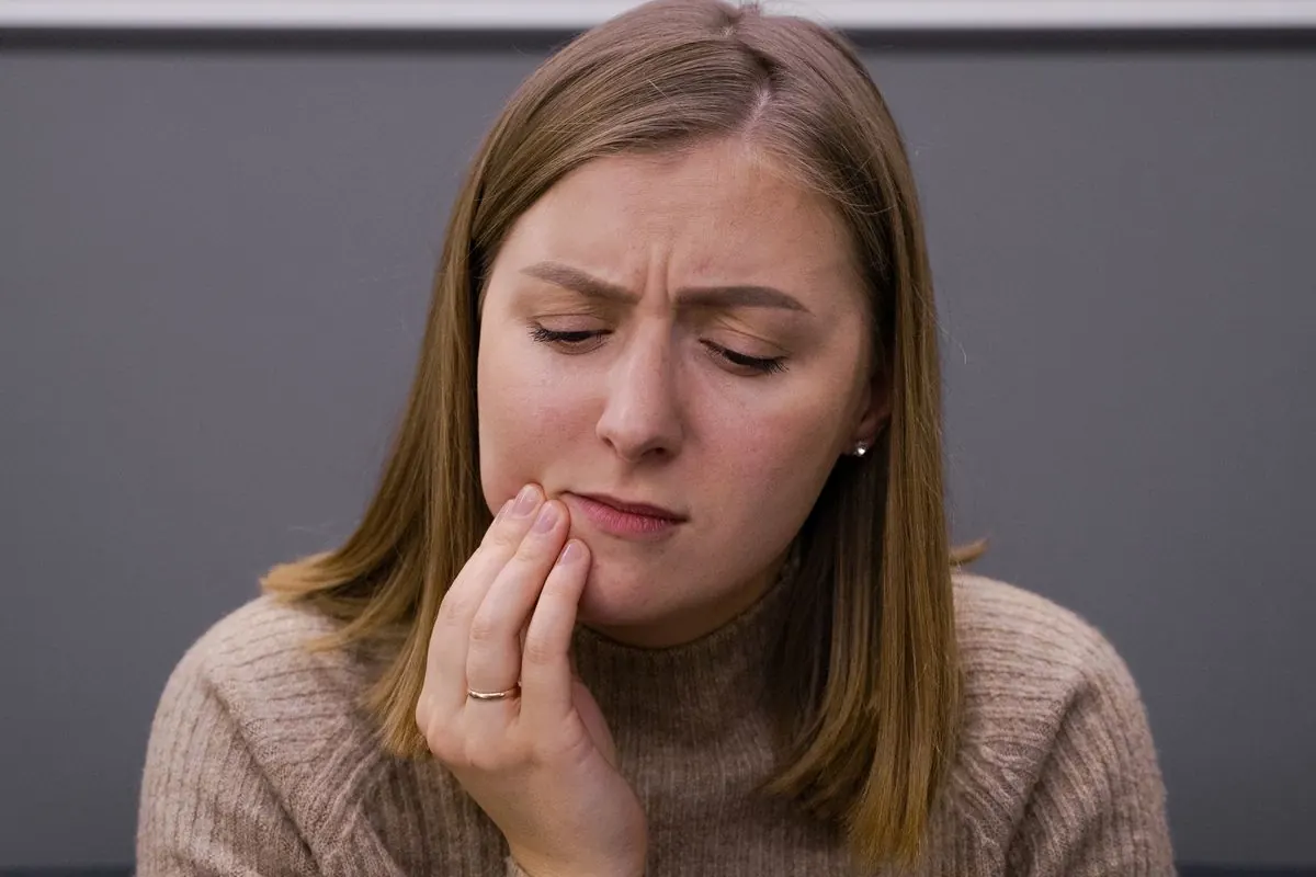 Woman holding her cheek in pain from a toothache