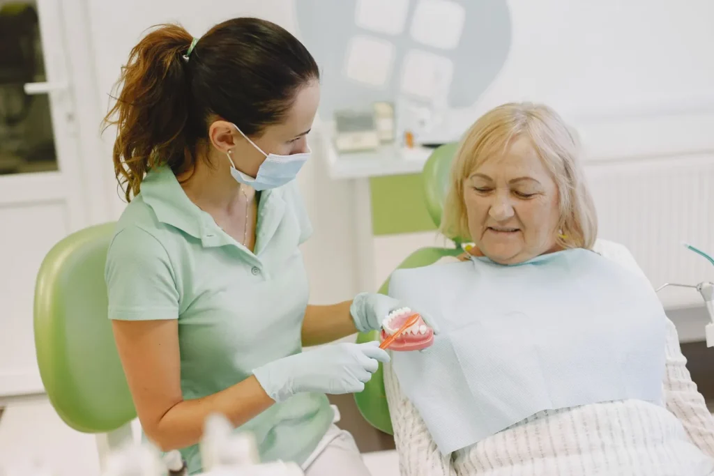 A dental team member showing a senior patient a denture model