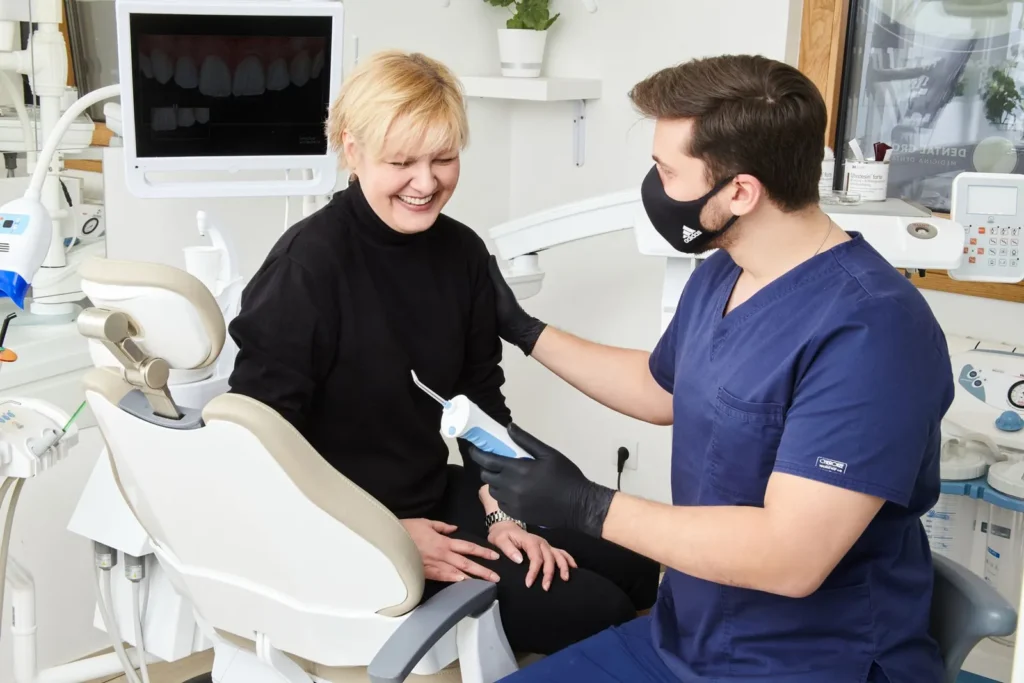 A dentist talking with a smiling patient in the dental chair