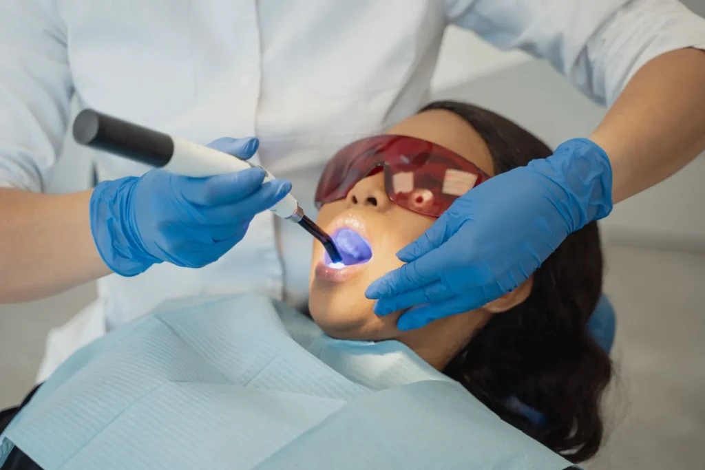 A dentist using a curing light to set a tooth-colored filling